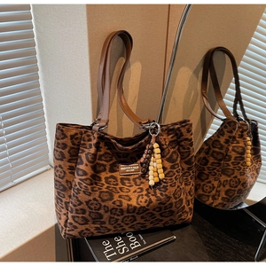 Detail of leopard print tote bag featuring leather handles and a colorful wooden bead tassel