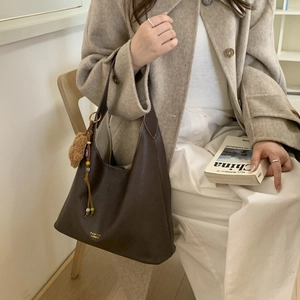 Detail of dark brown leather hobo bag with gold logo and plush charm accessory
