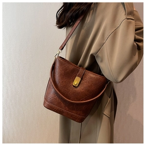 Close-up of brown vintage bucket bag with pleated texture and golden metal buckle