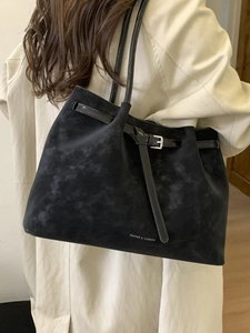 Minimalist black suede tote bag with decorative buckle strap and long shoulder handles