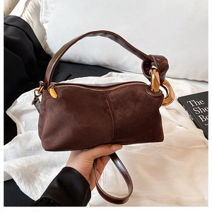Detail of dark brown suede handbag featuring a large golden metal ring and polished hardware