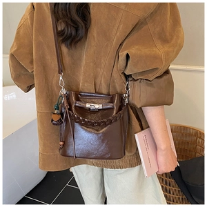 Detail of dark brown leather bucket bag featuring a woven handle and silver lock