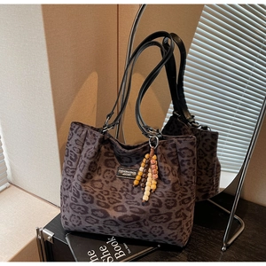 Close-up of leopard print tote bag fabric with leather label and beaded charm detail