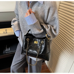 Nahaufnahme der schwarzen Stepptasche mit goldenem Schloss und eleganter Ledertextur