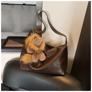 Détail d'un sac cabas marron foncé vintage avec un joli porte-clé en peluche lion