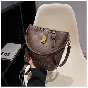 Close-up of vintage brown leather bucket bag with textured finish and golden buckle hardware