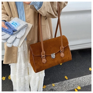 Close-up of caramel suede tote bag with vintage metal lock and slim shoulder straps