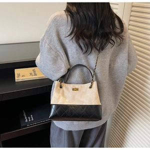 Detail der gesteppten Ledertasche mit goldenem Drehverschluss und Kettenriemen am Modell
