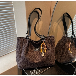 Detail of leopard print tote bag with leather handles and bohemian beaded pendant charm