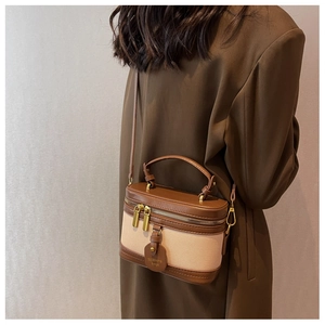 Sac seau en cuir marron et tissu beige porté par un mannequin en blazer marron