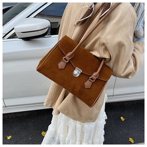 Detail of vintage brown suede shoulder bag with twin straps and metallic buckle hardware