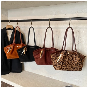 Detailansicht von vier minimalistischen Wildleder-Tote-Bags mit dekorativen Fransen
