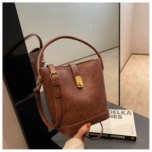 Macro side view of vintage brown bucket bag with wrinkled faux leather and gold buckle