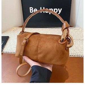 Detail of brown suede handbag featuring elegant gold chain link and smooth leather strap