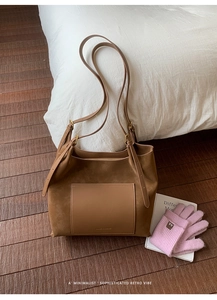 Detailed view of brown faux suede tote bag with leather pocket in a cozy lifestyle setting