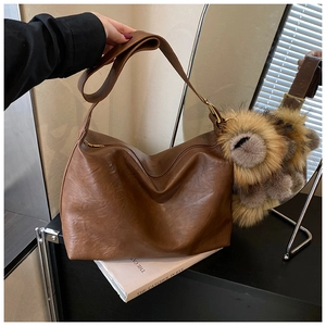 Détail de la texture d'un sac cabas marron vintage avec pendentif en peluche et zip