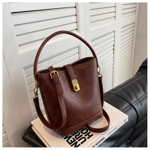 Detail of vintage brown bucket bag with cracked leather texture on stacked books