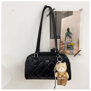 Detailed view of black quilted shoulder bag featuring a cute teddy bear plush charm
