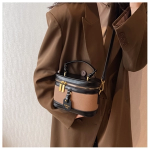 Dettaglio borsa a secchiello vintage con finiture in pelle marrone e zip dorata