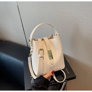 Detail of cream woven bucket bag with gold metal clasp on black art books