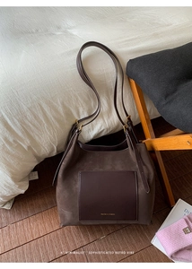 Detailed view of deep brown suede tote with leather pocket and gold brand logo