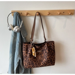 Detail of leopard print tote bag with leather tag and beaded charm on wall hook