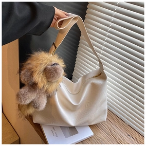 Détail du sac bandoulière blanc en similicuir avec un charm lion en peluche marron
