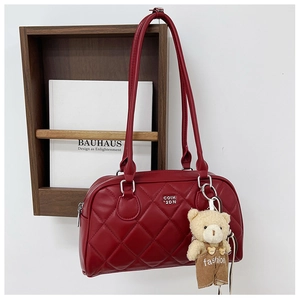 Detail of red quilted crossbody bag with metal logo and cute plush bear charm accessory