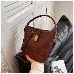Detail of dark brown leather bucket bag featuring vintage texture and metallic clasp