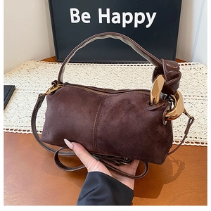 Detail of dark brown suede pillow bag featuring golden ring hardware and knotted handle design