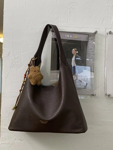 Dark brown leather tote bag with stylish teddy bear charm and sleek gold brand logo