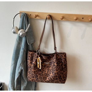 Detailed view of leopard print tote bag with brown leather tag and beaded charm