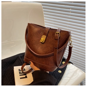 Detail view of a brown vintage bucket bag with leather texture and gold metal buckle