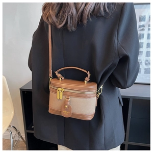 Détail d'un sac vanity en cuir marron et toile kaki porté en bandoulière par un modèle
