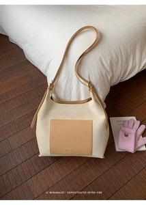 Detail of a large cream and camel tote bag with contrast outer pocket on wooden floor