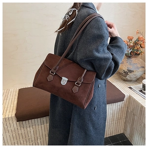 Detail view of dark brown suede shoulder bag with silver buckle on a gray wool coat
