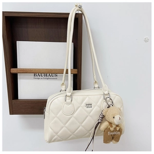 Detail of cream quilted bag with a brown teddy bear charm and silver metal rings