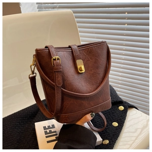 Detail of vintage brown bucket bag with marble leather texture and gold twist lock