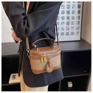 Dettaglio laterale della borsa a secchiello vintage marrone con cerniera dorata e logo