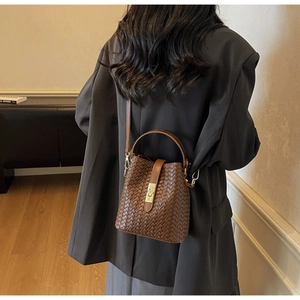 Detailed view of brown woven texture leather bucket bag with gold metal buckle
