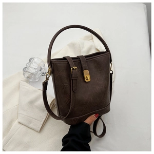 Detail of dark brown bucket bag featuring vintage texture and gold metal buckle accents