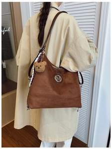 Détail du sac cabas en daim marron avec logo M argenté et pendentif ourson mignon