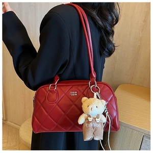 Detail of red quilted leather crossbody bag featuring a plush bear charm accessory