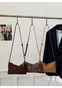 Détail des sacs bandoulière en daim mat en marron foncé, imprimé léopard et jaune