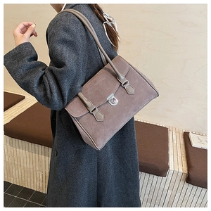 Detail of grey-purple matte shoulder bag featuring a silver metal lock and double straps