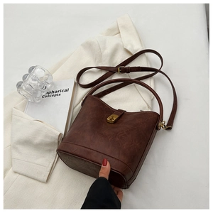 Detailed view of brown retro bucket bag with lychee grain texture and gold metal clasp