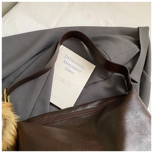 Gros plan du sac vintage marron avec pompon en fourrure sur un blazer gris