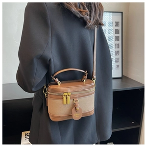 Détail d'un sac seau vintage en cuir marron et toile avec deux fermetures éclair dorées