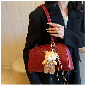 Detail of red quilted bowling bag with glossy finish and cute teddy bear pendant charm