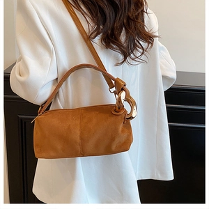 Detail of brown faux suede baguette bag featuring golden chain and slim shoulder strap